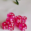 A close-up of a pile of bright pink transparent dice with white dots on a white surface.