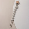 A silicone bear paw pacifier clip with a wooden top and a metal clip attached to a chain.