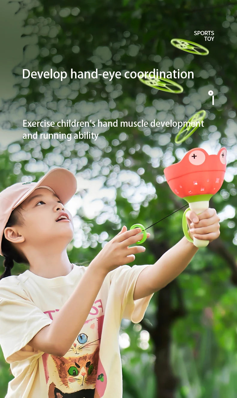 A young girl is playing with a red and green pull-string flying saucer launcher toy outdoors.