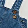 Close-up of a denim romper featuring button details and stitching.