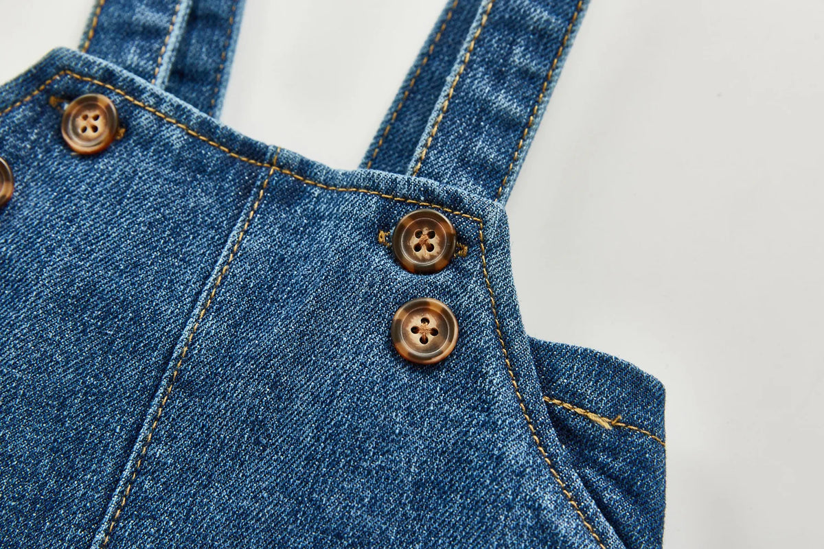 Close-up of a denim romper featuring button details and stitching.