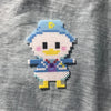 A white and blue fuse bead figure resembling a bird is crafted using small plastic beads on a gray fabric background.