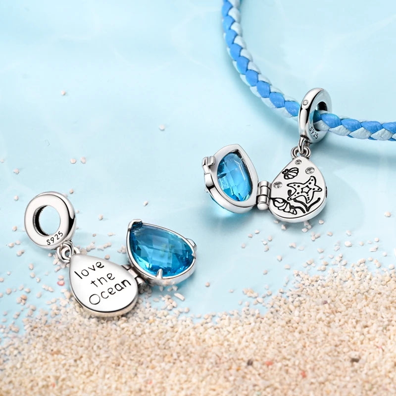 Sterling silver charm pendant set featuring blue gemstone and marine life charms on a blue beaded necklace