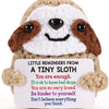 A handmade crochet plush sloth with brown and white fur, smiling, featuring a positive message.