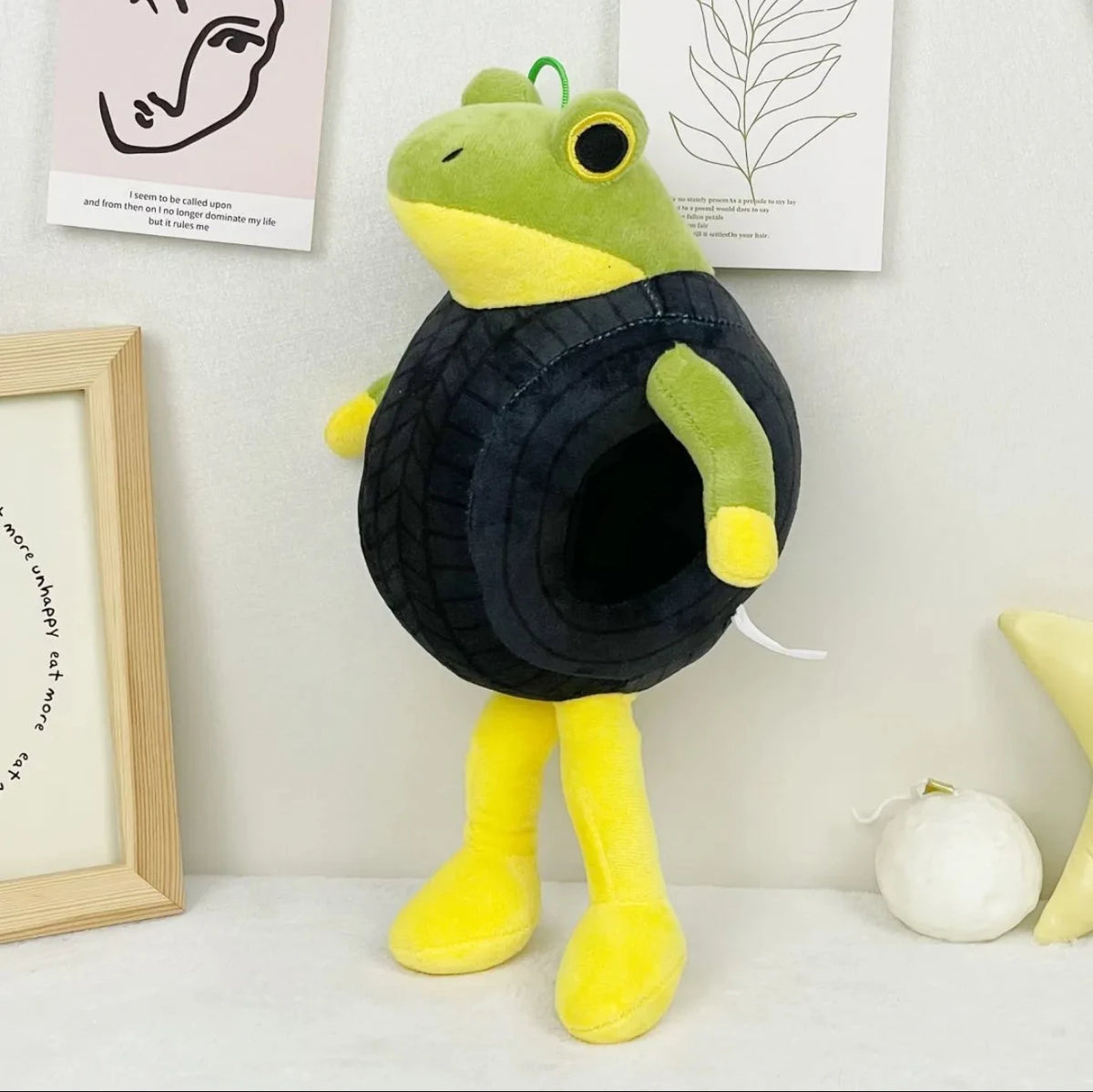 A soft, green and yellow shark plush toy with black accents sitting on a white surface.