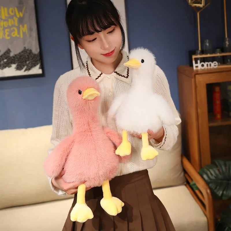 A woman holds two realistic call duck plush toys, one pink and one white, against a blue background.
