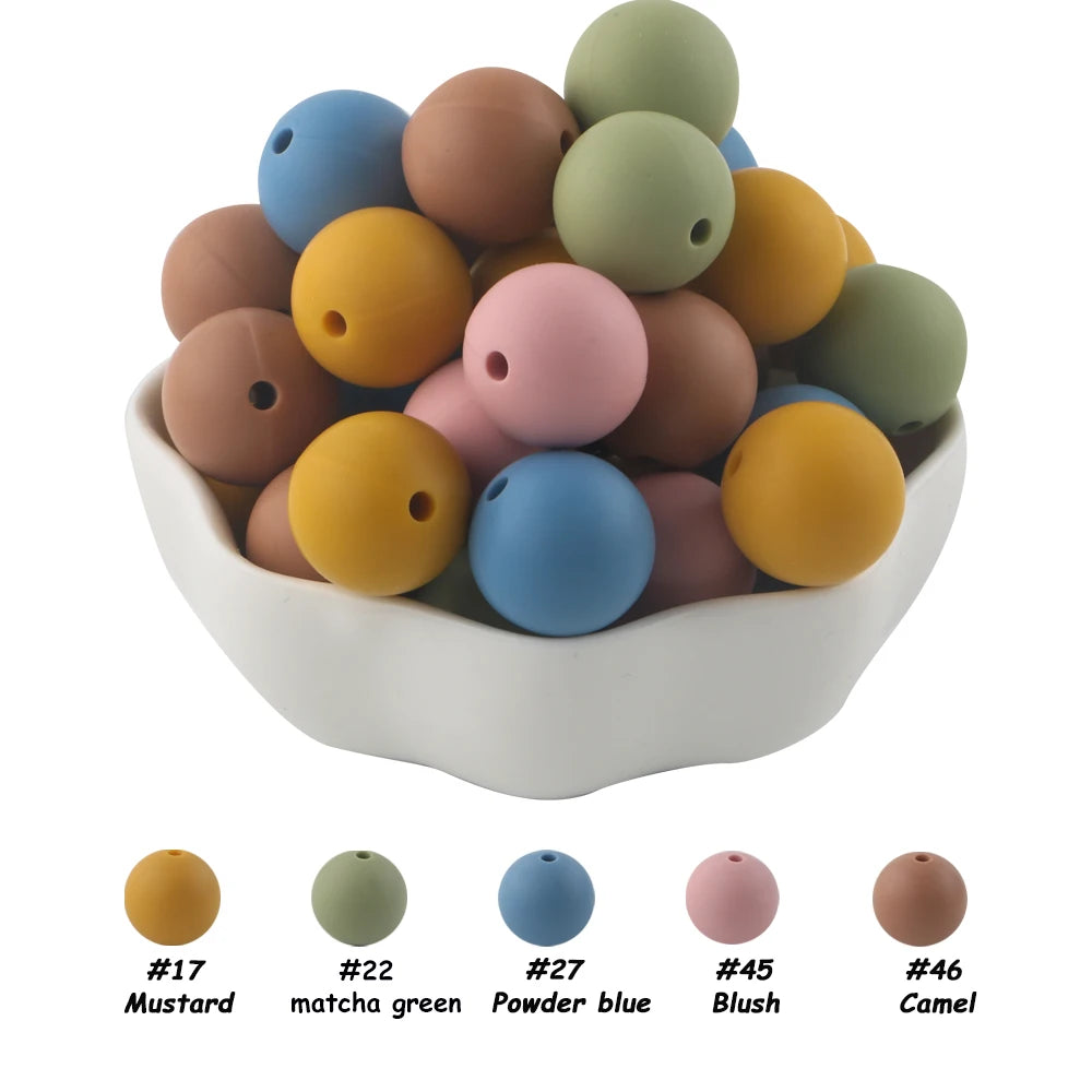 A pile of 50 silicone beads in assorted colors including mustard, matcha green, powder blue, blush, and camel tones.