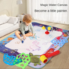 A child is drawing on a large magic water canvas mat with various pens and colorful items.