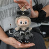 A small, fluffy doll wearing a black and white checkered outfit with a bow is held in a person's hand.