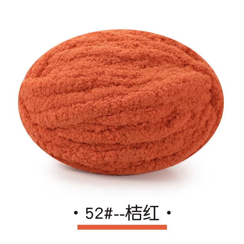 A ball of orange-red chunky chenille yarn for hand knitting projects.