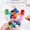 Hands are using a wooden spoon to transfer colorful balls from a bowl, demonstrating hand-eye coordination training.