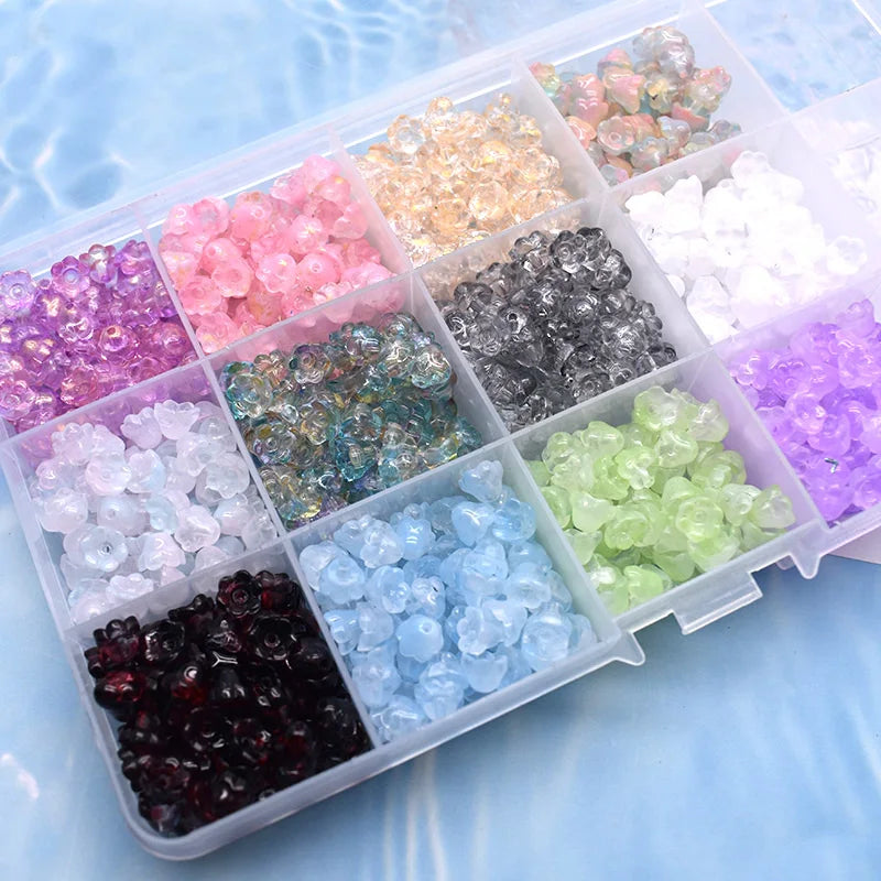 A clear plastic box filled with various colors of glass beads, including pinks, purples, greens, and clear tones.