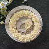 A white silicone mold shaped like a wreath of rose leaves for cake and chocolate decorating