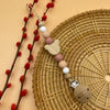A string of wooden and silicone beads is displayed on a woven mat next to red berries.