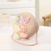 A round, light pink handwoven straw crossbody bag decorated with a sparkling butterfly and lace bow.