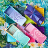 A collection of diamond painting organizer trays in various colors including purple, yellow, pink, and blue, arranged on a fl