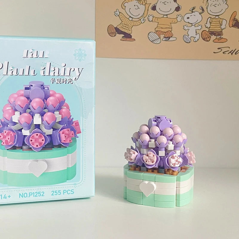 A set of miniature flower bouquet building blocks in purple and pink on a light green base.