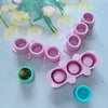 A collection of pink and teal silicone molds for DIY succulent plant pots arranged on a light blue surface.
