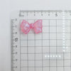 A pink shimmer mermaid bowknot bead is shown against a ruler for scale.