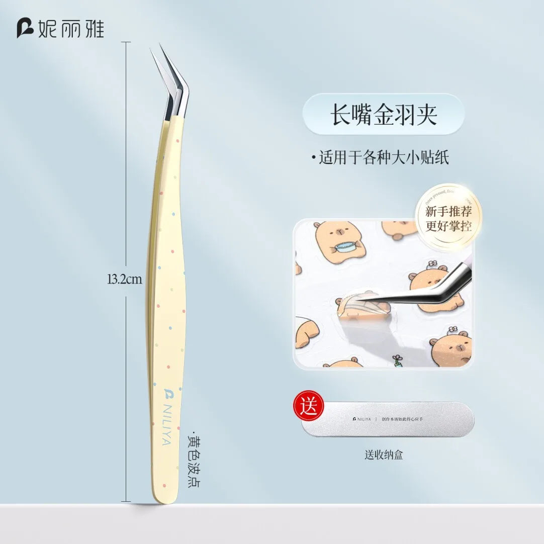 A pair of long stainless steel tweezers used for sticker crafting, shown next to a small bear-shaped object.