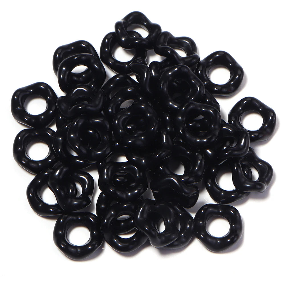 A pile of black acrylic spacer beads shaped like doughnuts for jewelry making