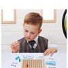 A young boy is shown interacting with a wooden Montessori multiplication board game featuring colorful tiles and numbers.