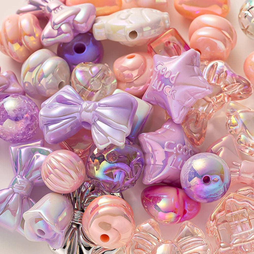 A collection of iridescent acrylic bow and flower beads in pink, purple, and clear shades for DIY jewelry making