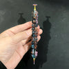 A hand holds a colorful diamond painting pen with a stainless steel tip, displaying iridescent and multi-toned colors.