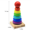 A stack of six colorful wooden geometric shapes, stacked vertically on a light wooden base.