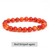A close-up of a red striped agate stretch bracelet with polished, translucent beads.