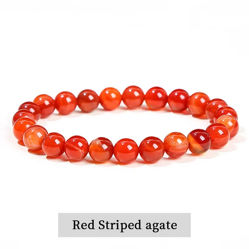 A close-up of a red striped agate stretch bracelet with polished, translucent beads.