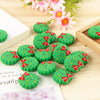 Green Christmas tree silicone beads with red ribbon accents arranged on a wooden surface.