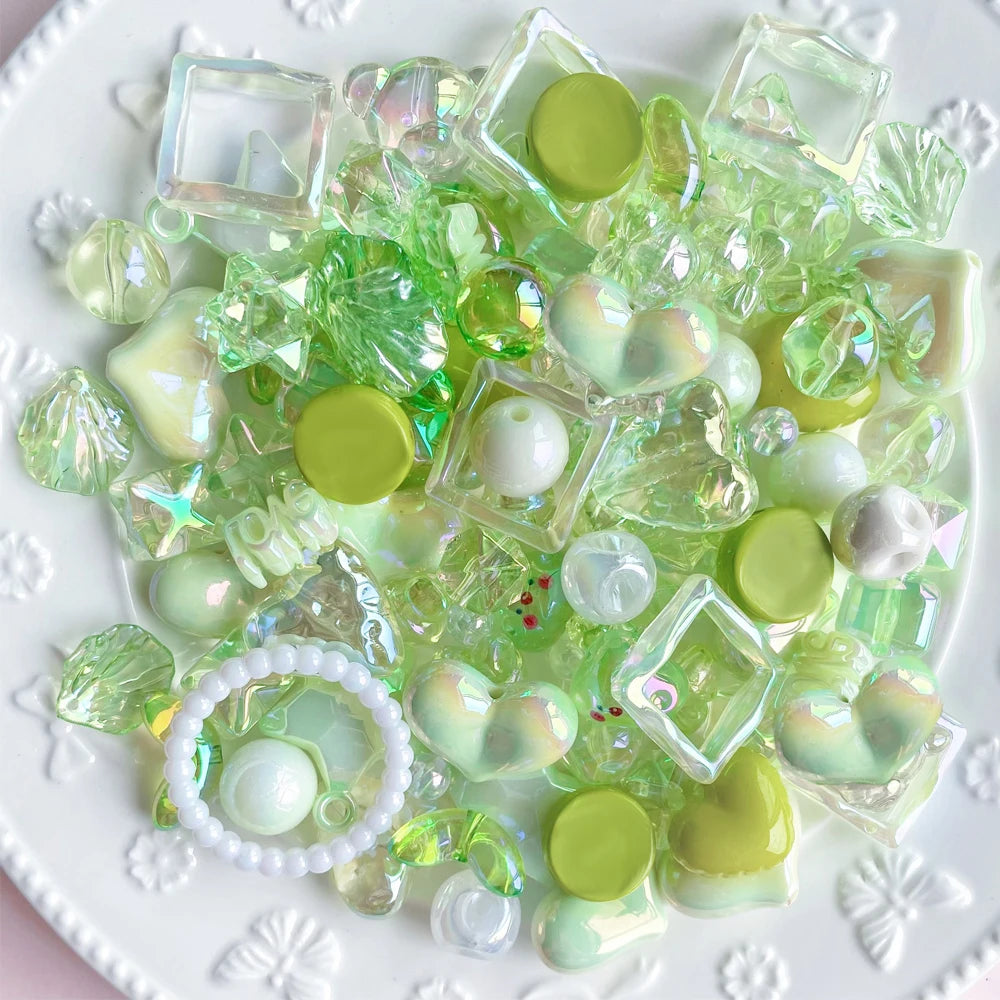 A collection of clear and green acrylic bow and flower beads used for DIY jewelry making