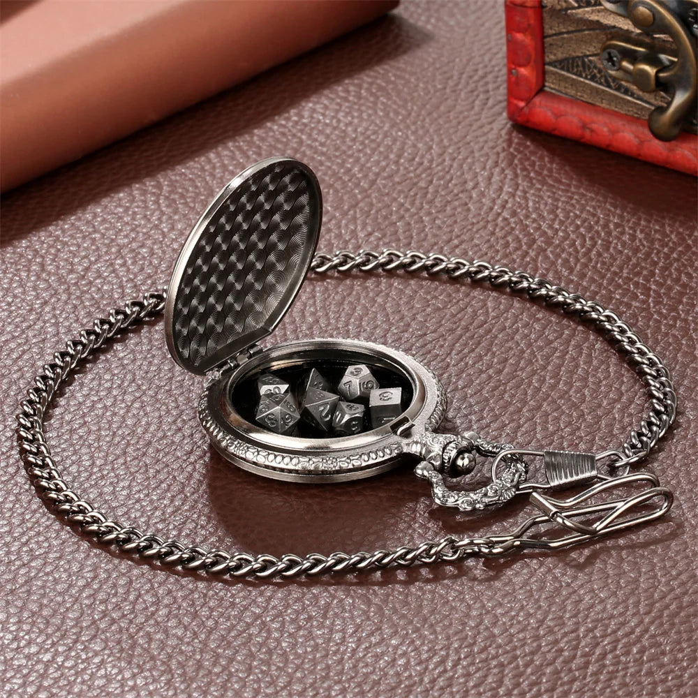 A silver steampunk dragon pocket watch dice case with a textured lid and a chain is displayed on a brown leather surface.