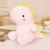 A pink dinosaur plush toy with yellow spikes and a pink nose sitting on a white surface.