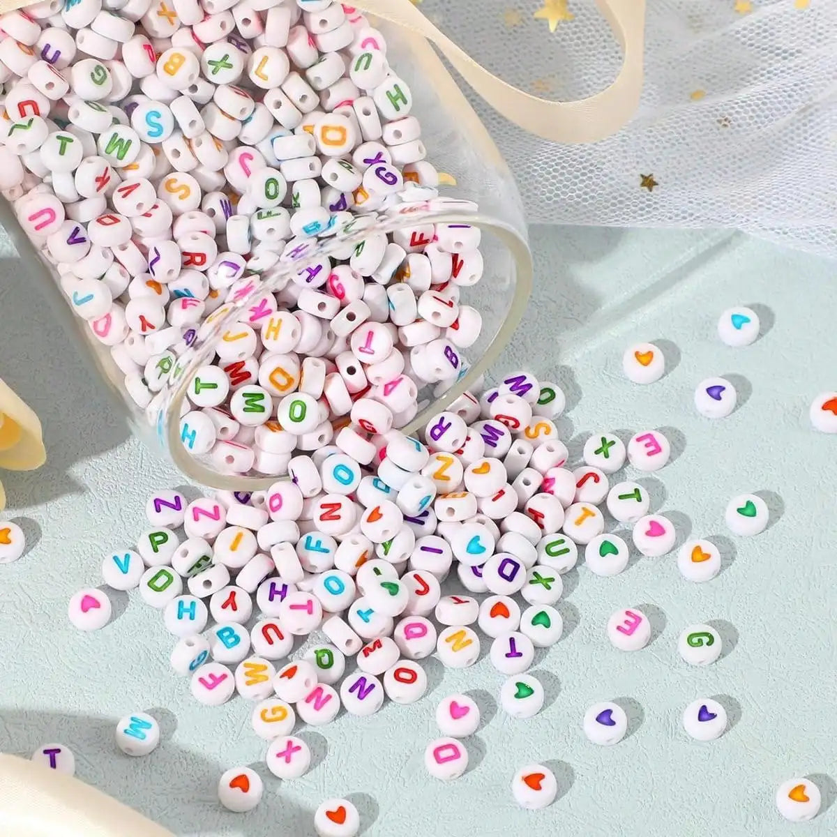 A pile of colorful letter and number acrylic beads scattered on a light blue surface with a clear container nearby.