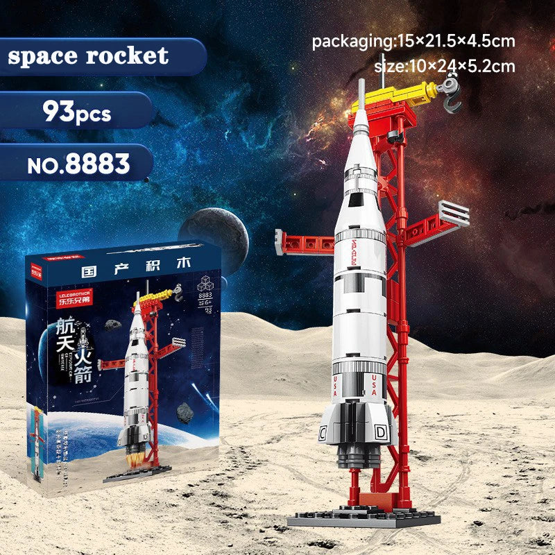 A white space rocket model is displayed on a red stand, next to its packaging and building blocks.