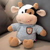 A soft plush cow doll with white and brown markings, sitting on a light surface.