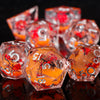 A close-up of a set of translucent orange resin dice with red plum blossom designs, reflecting on a dark surface.