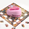 A pink lever action embosser tool rests on a floral patterned mat.