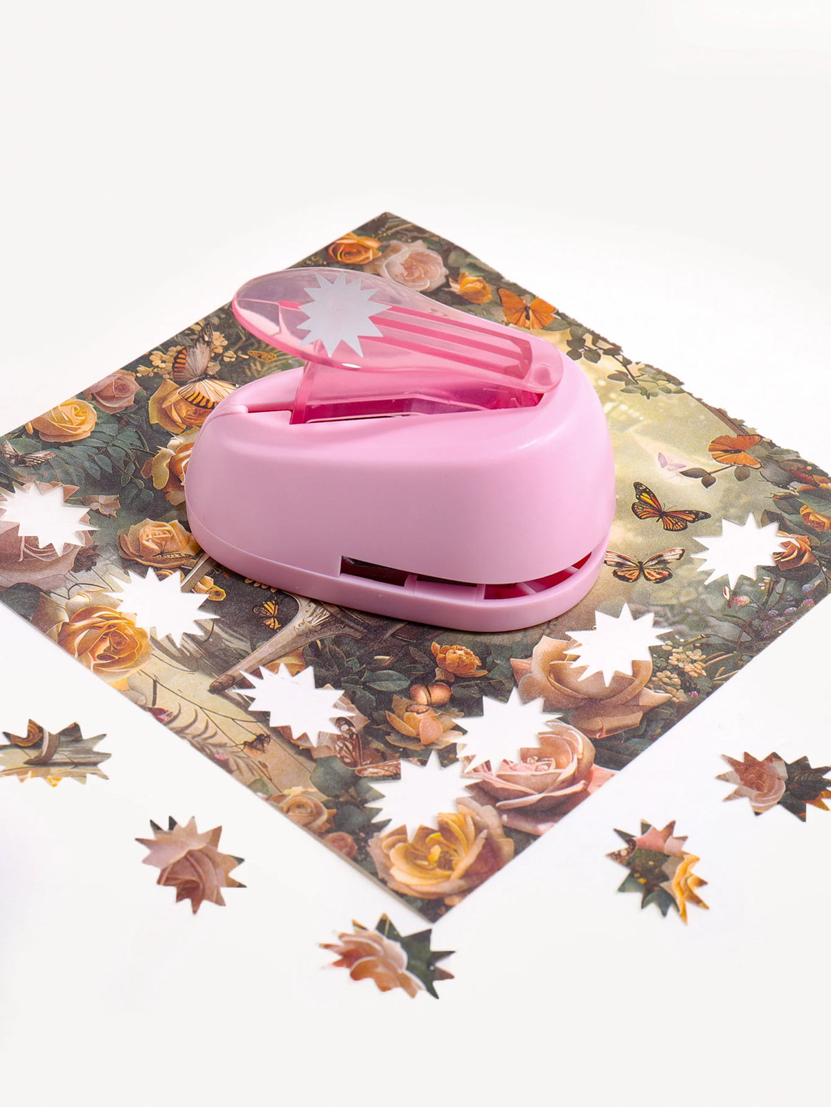 A pink lever action embosser tool rests on a floral patterned mat.