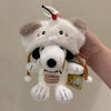 A white Snoopy plush keychain charm with black ears and a red bow is held in a hand.