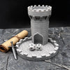 A gray medieval castle dice tower with a tray and a sword on a stone surface.