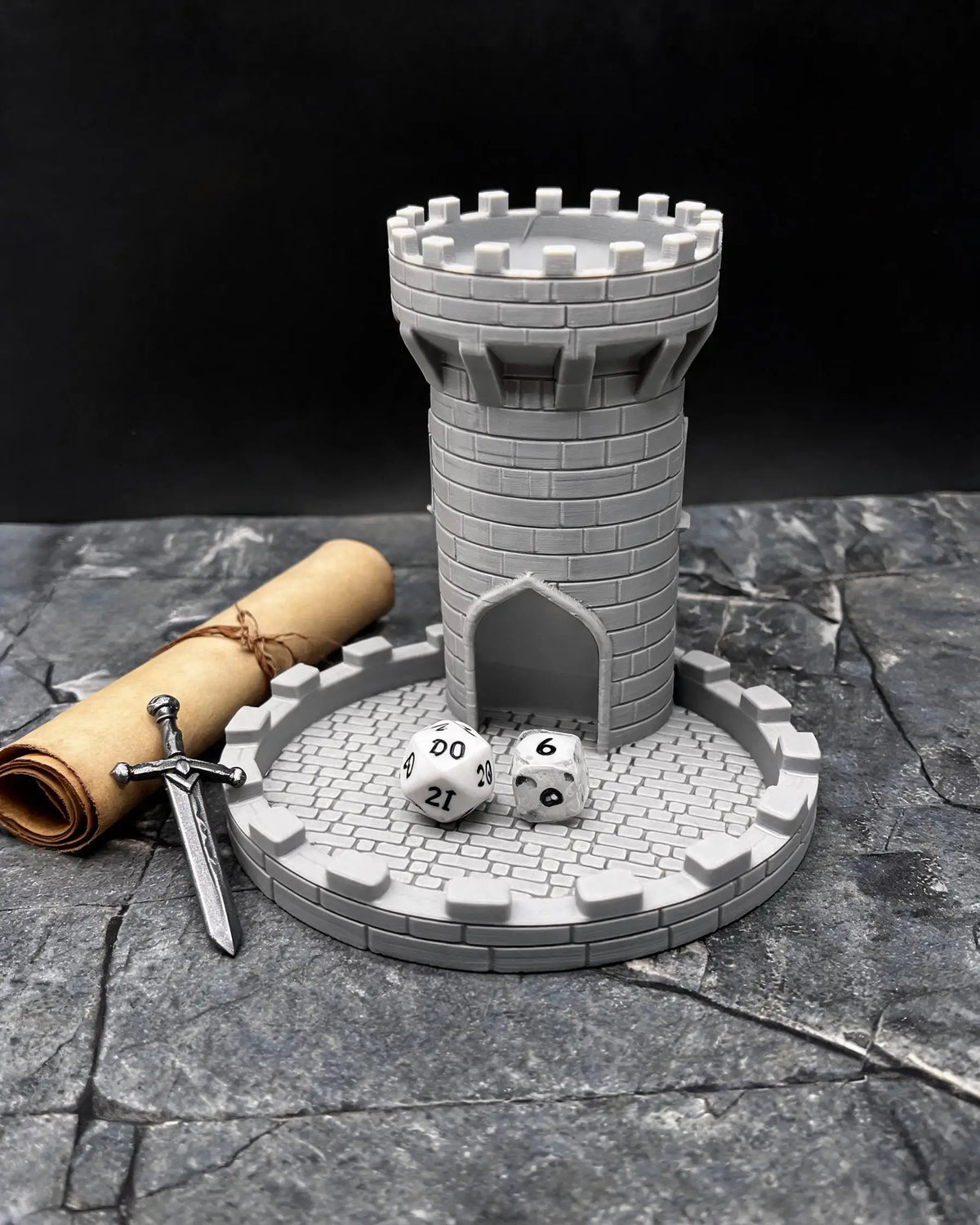 A gray medieval castle dice tower with a tray and a sword on a stone surface.