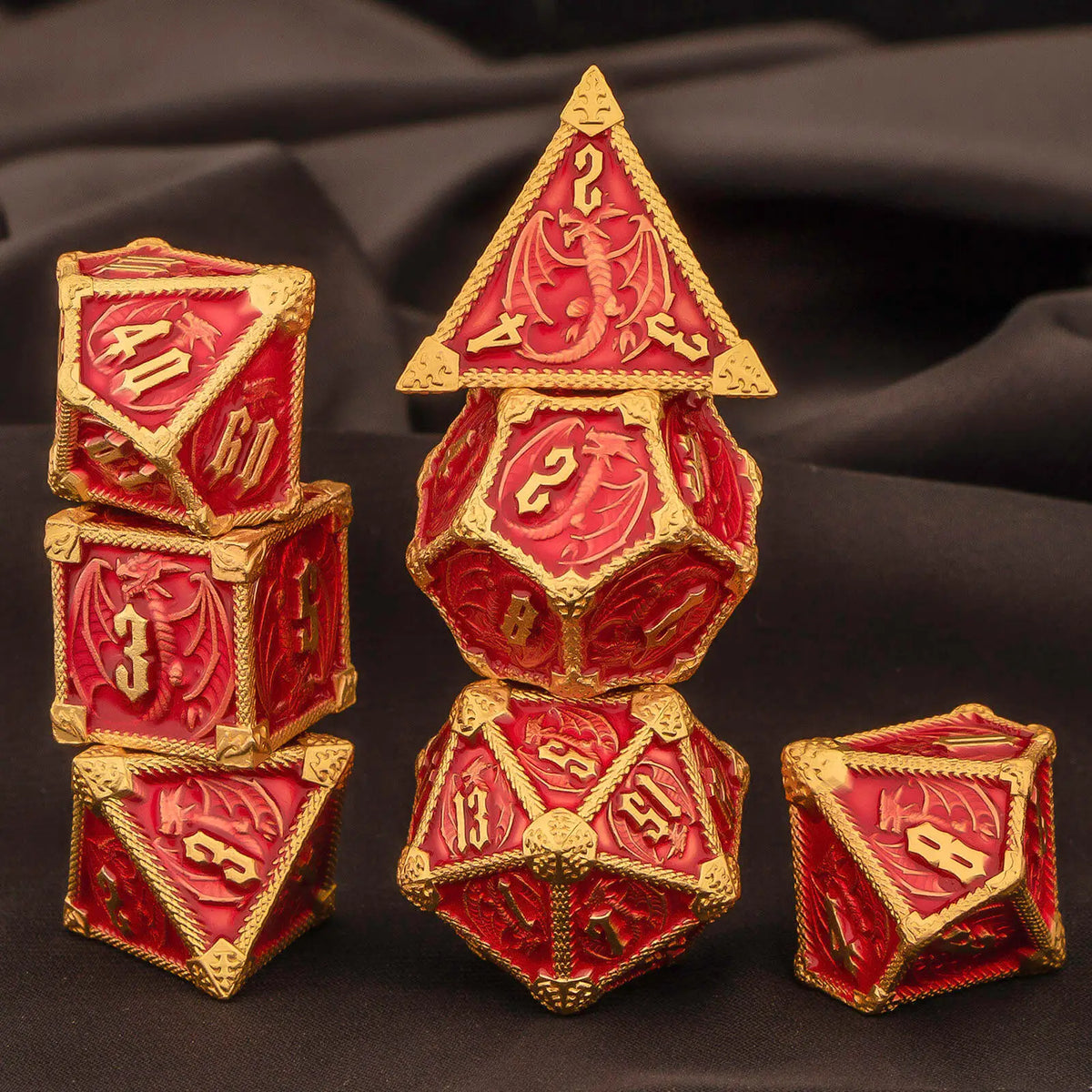 A set of seven polyhedral metal dice in red and gold on a dark background.