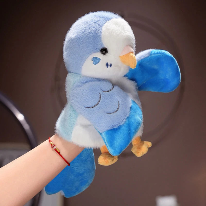 A cute blue and white parrot plush finger puppet being held by a hand.
