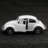 A white 1:38 die-cast model of a classic Beetle car shown in profile on a dark surface.