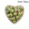 A bowl filled with ten small, round, printed silicone beads in shades of green and pink flowers for DIY jewelry making