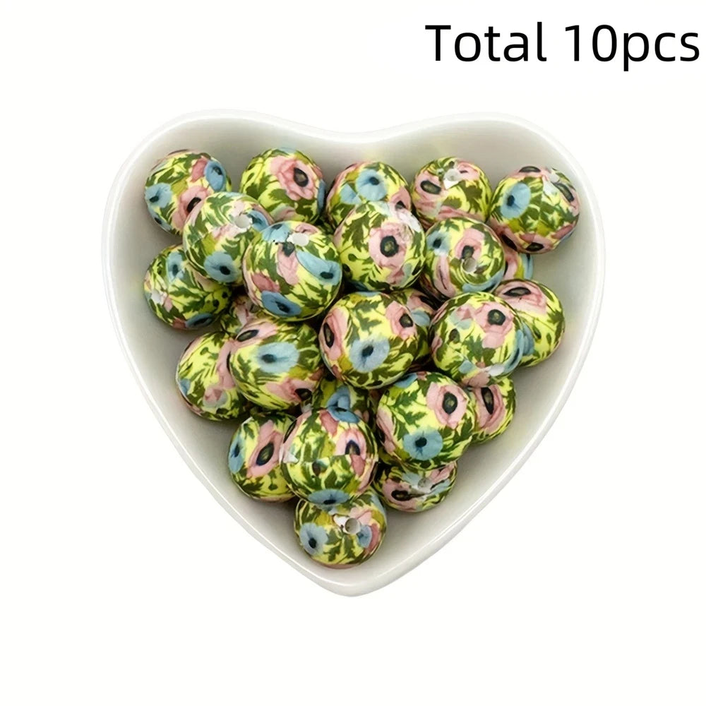 A bowl filled with ten small, round, printed silicone beads in shades of green and pink flowers for DIY jewelry making