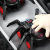 A hand is interacting with a black and red inertia-powered spider crawling toy car.
